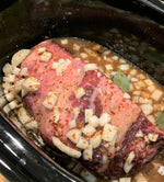 raw mariposa ranch grassfed beef brisket inside a slow cooker.  It is surrounded by onions, seasonings, and beef broth